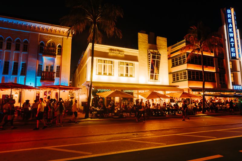 Crowds enjoying art deco nightlife on Ocean Drive under illuminated neon signs