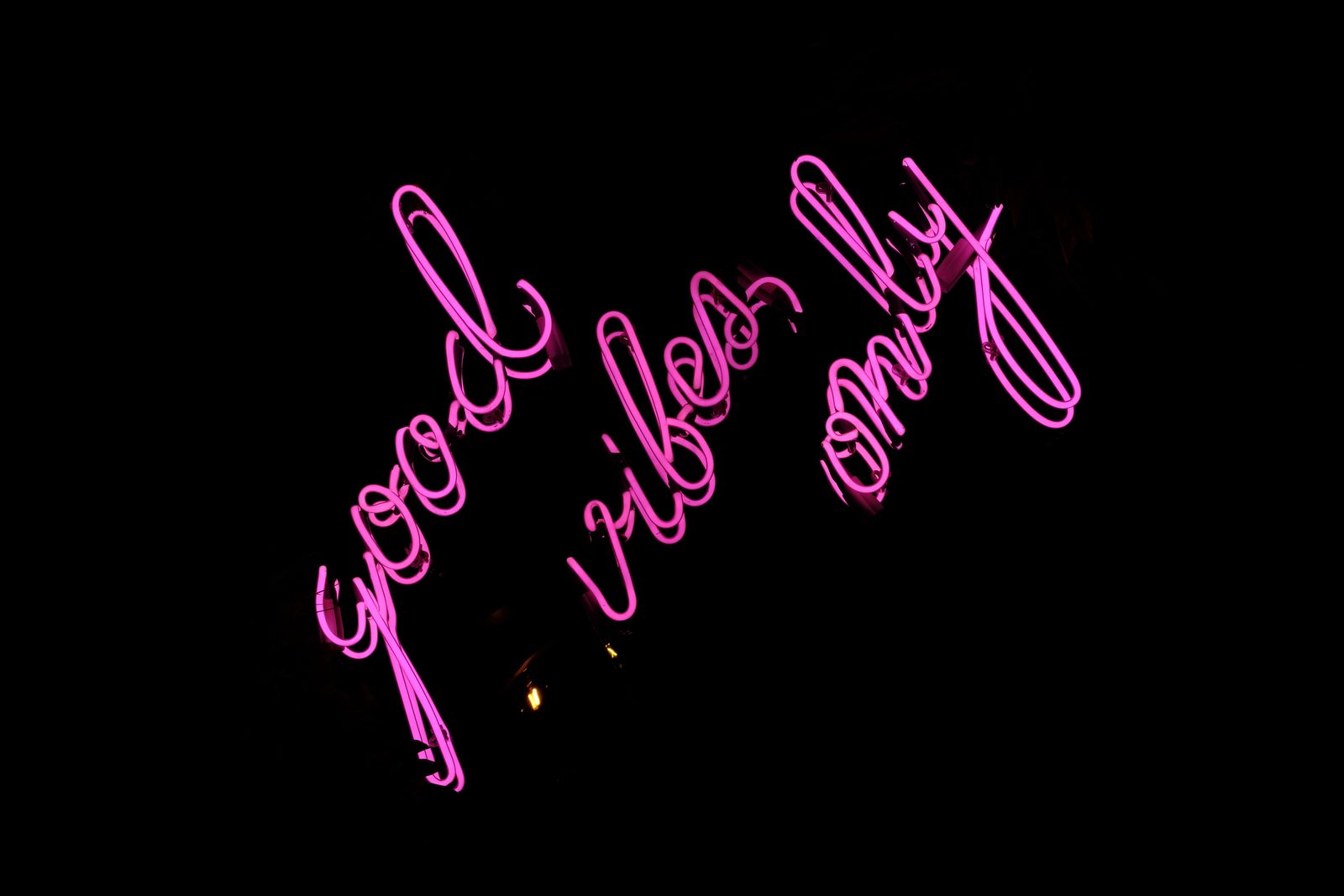 Pink neon sign reading 'good vibes only' glowing in the dark