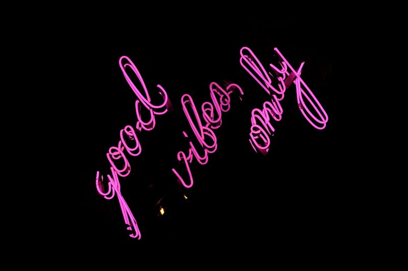 Pink neon sign reading 'good vibes only' glowing in the dark