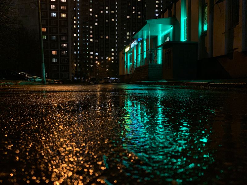 Rain-soaked street reflecting city lights at night